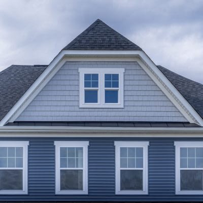 Gable with horizontal vinyl lap siding, double hung window with white frame, shingle facade on a pitched roof attic at an American luxury single family colonial home neighborhood in the USA